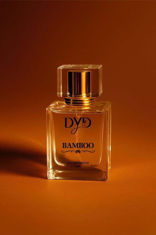 DYD BAMBOO Eau de Parfum bottle showcasing its elegant design against a warm orange background.